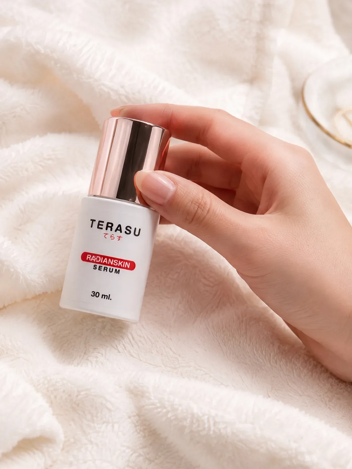 มือถือขวดเซรั่ม TERASU บนผ้าสีขาวนุ่ม